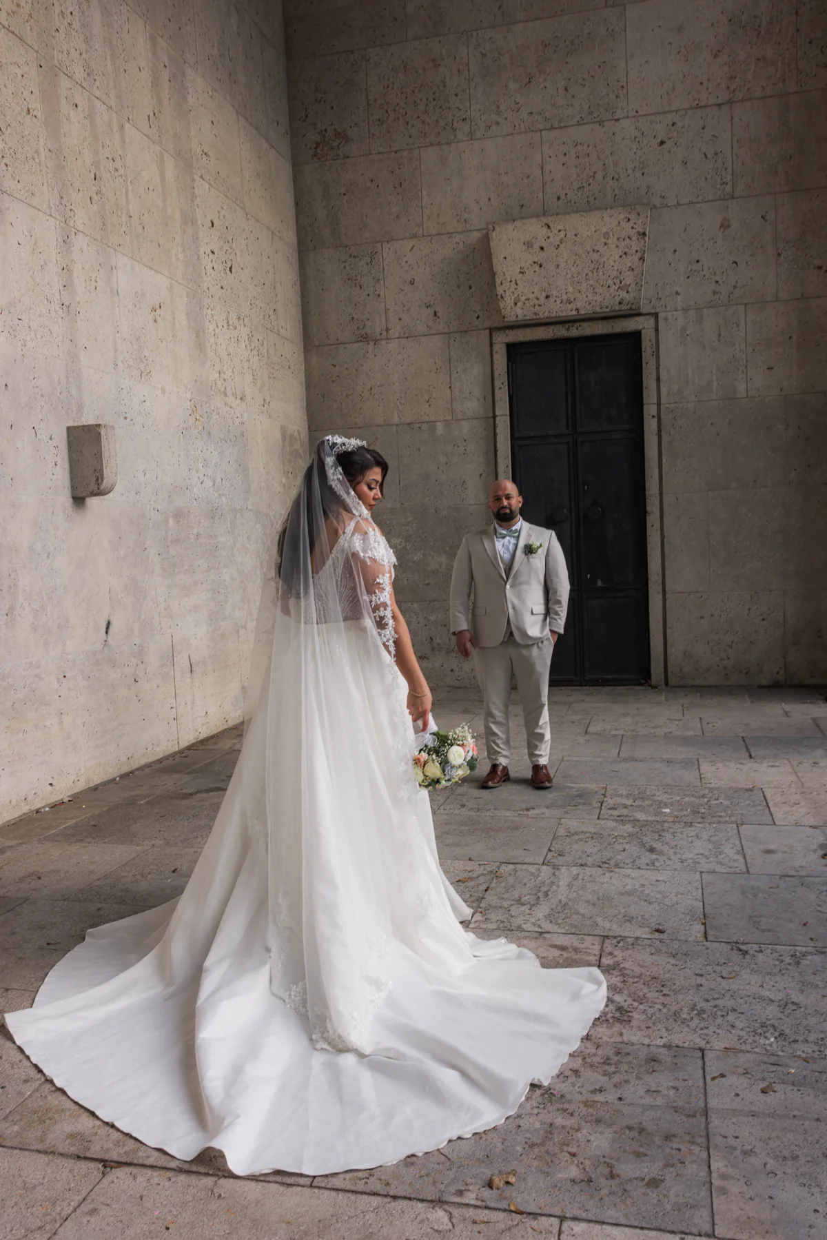 Ein Brautpaar im steinernen Innenhof, das Brautkleid mit langer Schleppe