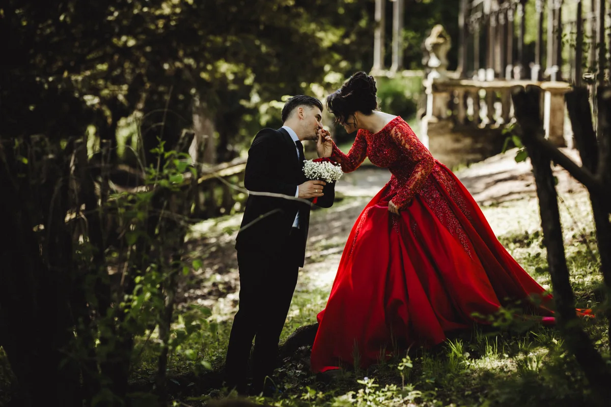 Ein Paar im roten Festkleid und dunklen Anzug im Garten