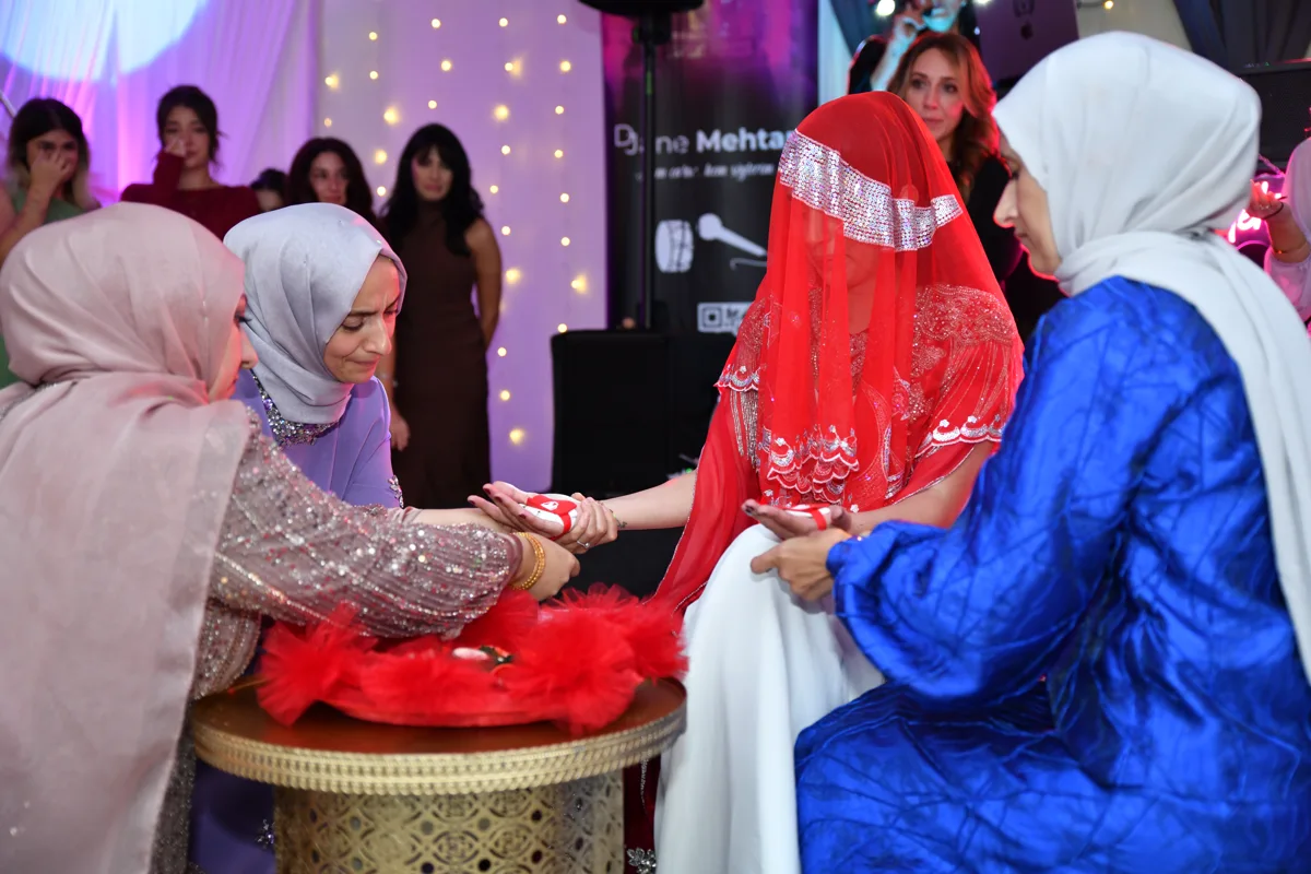 Eine Braut unter rotem Schleier bei ihrer Henna-Zeremonie