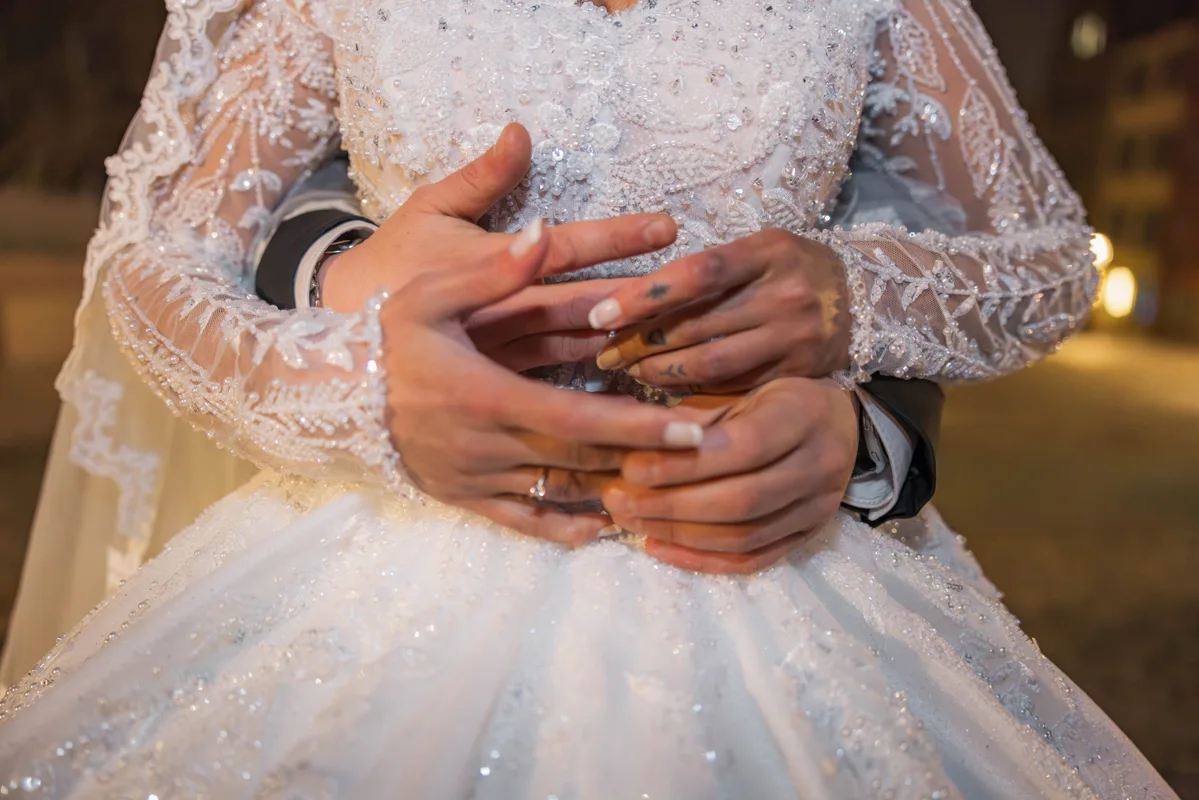 Die Hände eines Hochzeitspaars in einer Umarmung