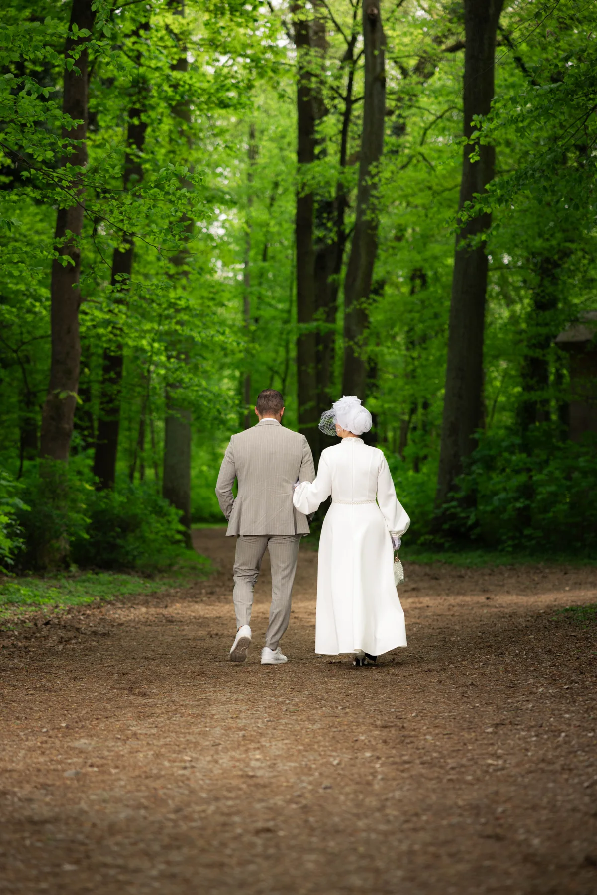 Ein Brautpaar geht Hand in Hand durch einen grünen Wald