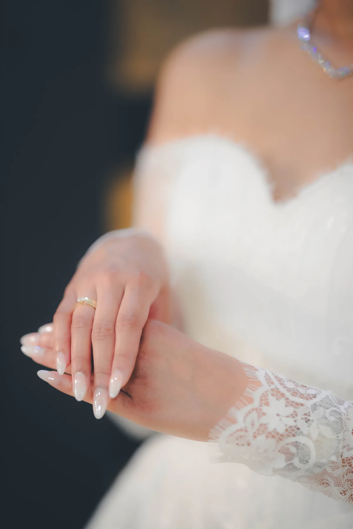 Gefaltete Hände einer Braut mit Spitzenhandschuhen